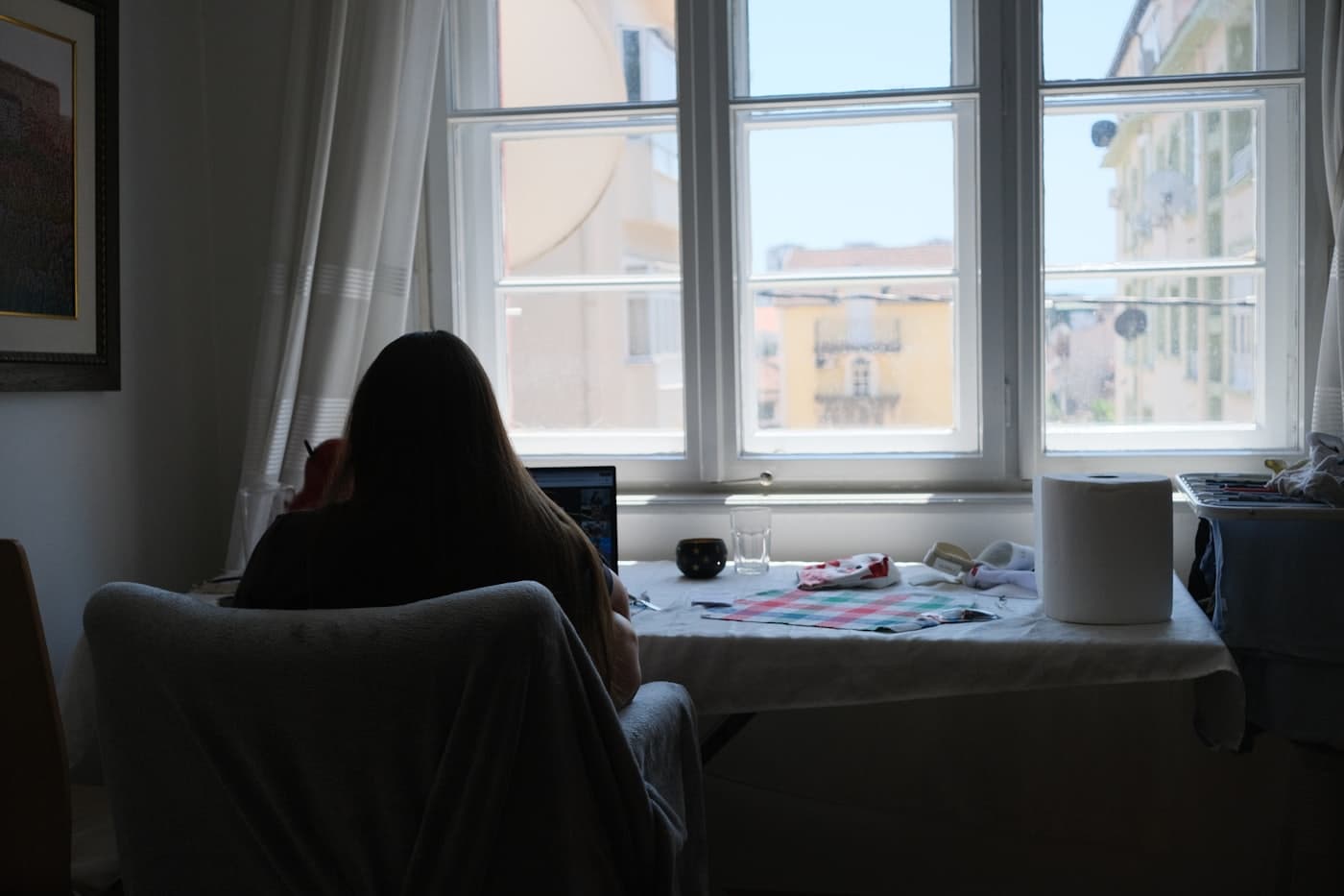 Persona estudiando con una laptop junto a una ventana